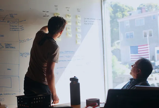 2 people looking at a strategy plan on a white board